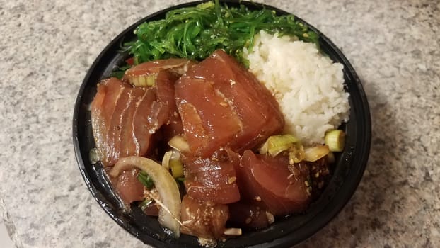 raw tuna and rice and onions in plastic container on counter