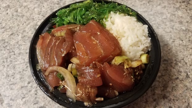 raw tuna and rice and onions in plastic container on counter