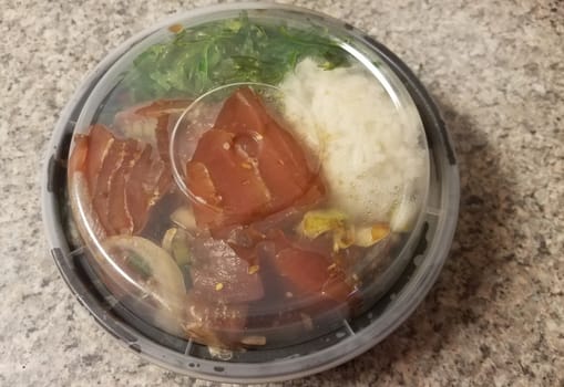 raw tuna and rice and onions in plastic container on counter