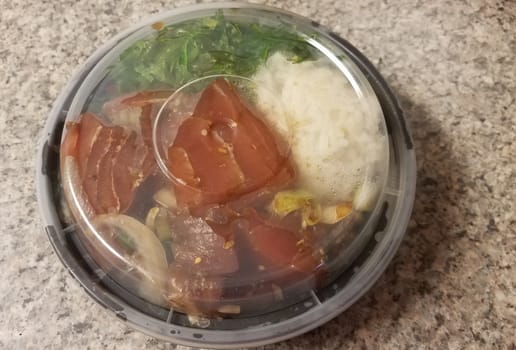 raw tuna and rice and onions in plastic container on counter