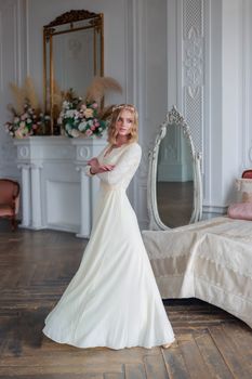 Full-length portrait of a bride in a beautiful lace wedding dress in the interior of a white studio