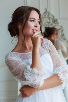 Close-up portrait of a bride in a white wedding dress looks attentively aside.