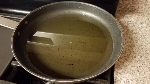 dirty frying pan on stove with used cooking oil