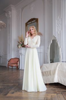 Full-length portrait of a bride in a beautiful lace wedding dress in the interior of a white studio