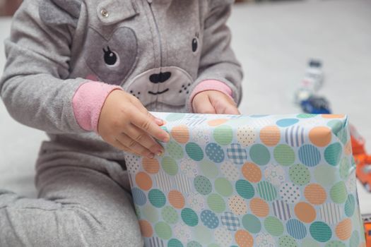 Adorable little Child unpacks gifts sitting on the bed.