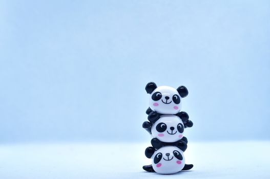 Little panda stacked porcelain figurines isolated on black background