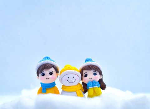 Tourism and travel concept: Miniature people in winter snow along with little snowman