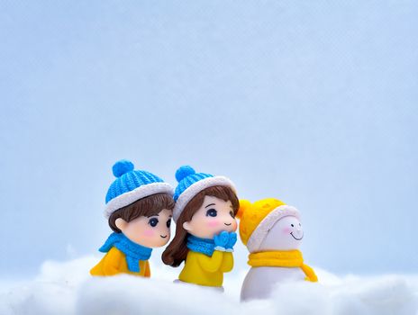 Tourism and travel concept: Miniature people looking for something in winter snow along with little snowman