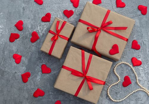 Romantic background with gifts tied with a red ribbon and red hearts on concrete