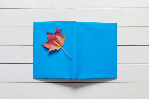 .The book with a bookmark of fallen leaves text on a wooden background