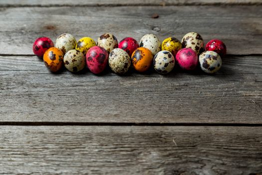 Multi-color dyed easter eggs arranged in a row on wooden background. Easter background with space for a text.