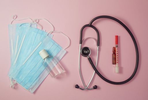 Covid-19, coronavirus treatment. Pills, stethoscope and medical masks, vaccine on pink background.