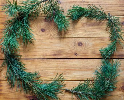 frame of pine branches with cones on a wooden background.