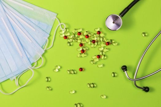 Covid-19, coronavirus treatment. Pills, stethoscope and medical masks on green background.