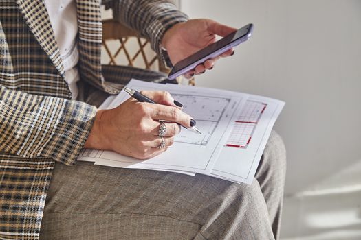 Woman interior designer with interior plans for a new project holds a pen in her hands, freelancer talks with a customer.Soft focus