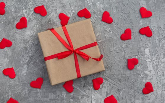 Romantic background with gifts tied with a red ribbon and red hearts on concrete