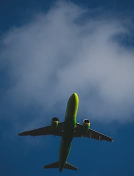 Silhouette of a green plane taking off against a blue sky
