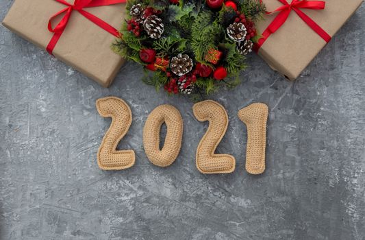 .Christmas background with knitted numbers 2021, gifts tied with a red ribbon and decorative wreath