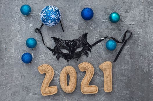 Christmas background with knitted numbers 2021 masquerade lace mask.