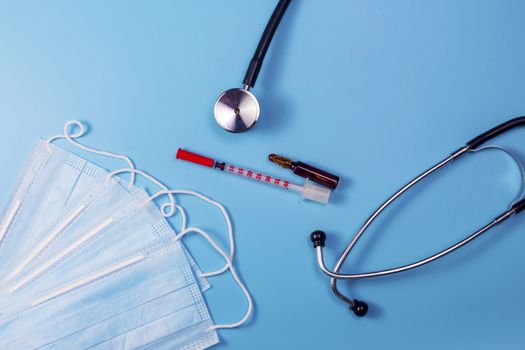 Covid-19, coronavirus treatment. Pills, stethoscope and medical masks on blue background.