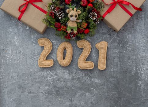 .Christmas background with knitted numbers 2021, gifts tied with a red ribbon and decorative wreath