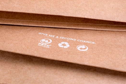 Reuse concept. Words on paper SECOND CHANCE. Words GIVE A CHANCE. Craft paper with recycle icons. Eco packaging background. Light brown recycled paper texture. Recycle icons on brown paper.