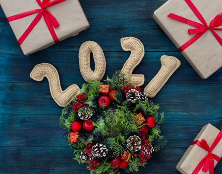 .Christmas background with knitted numbers 2021, gifts tied with a red ribbon and decorative wreath