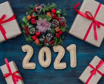 .Christmas background with knitted numbers 2021, gifts tied with a red ribbon and decorative wreath