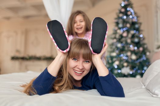 Little girl spends time playing with mom while lying in bed. Christmas tale. Happy childhood.