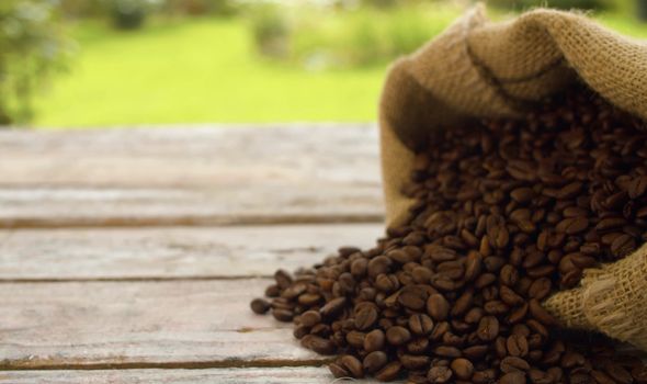 Close-up coffee beans in a burlap jute sack on a wooden table outdoors. Zoom shot