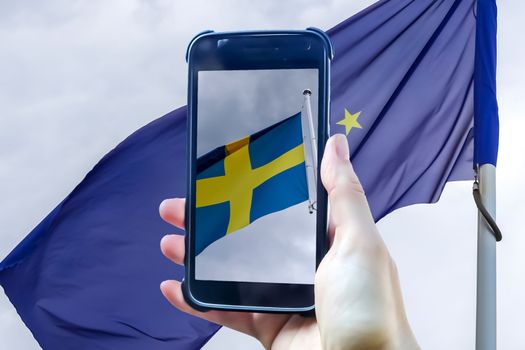 Sweden flag in a smartphone display in front of a european union flag