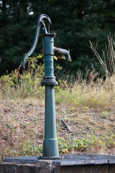 antique iron water pump with handle stands in the garden