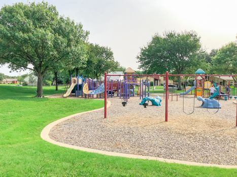 Swing set at large playground in residential neighborhood near Dallas, Texas, America. Community park with row of single family houses in background