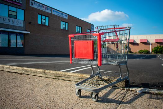 ELKINS PARK, PENNSYLVANIA-MAY 25,2020: A Lone Shopping Cart Rests at the Edge of an Empty Parking Lot. Businesses are struggling due to COVID-19.