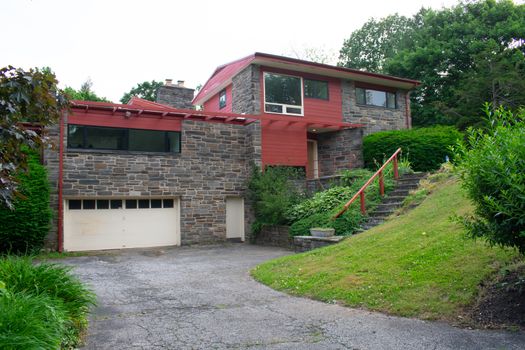 A Modern Cobblestone House With a Red Trim and a Red Roof and Driveway