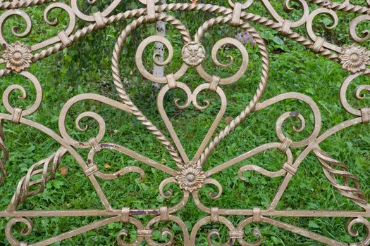 Forged elements on a garden bench in the shape of a heart.Garden wrought iron furniture in the garden.