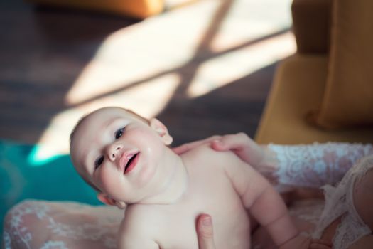 Little boy leaned back in mom's arms and looking at the camera smiling