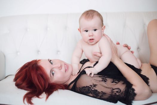 The baby boy sits astride mom's belly and smiles