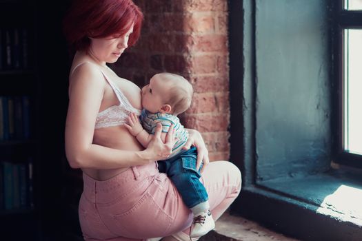 A young mother is breastfeeding her little child and looking at him tenderly