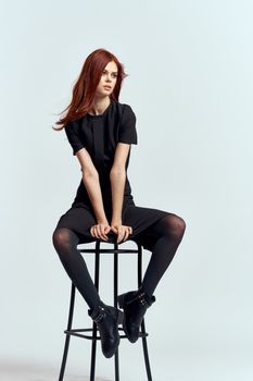 woman high chair indoors full length black dress red hair model boots. High quality photo