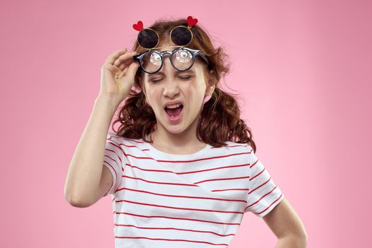 Cheerful girl with pigtails sunglasses striped t-shirt lifestyle pink background. High quality photo