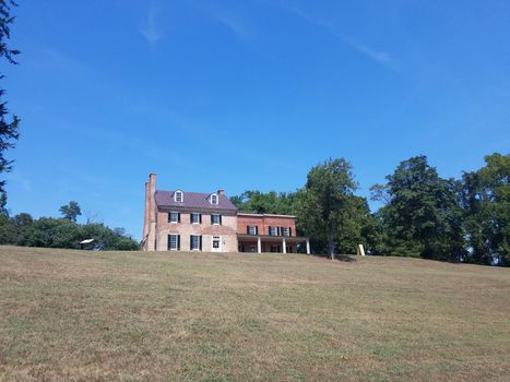 grassy hill with brick house or home and trees