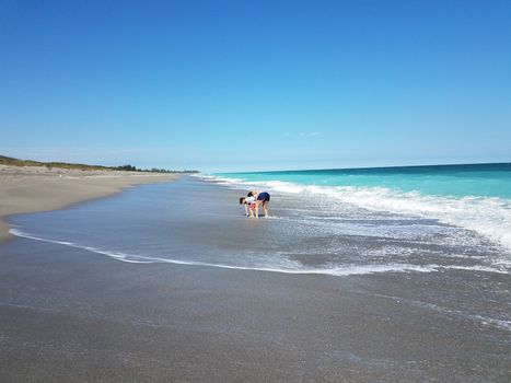 mother and child playing on the beach sand with waves