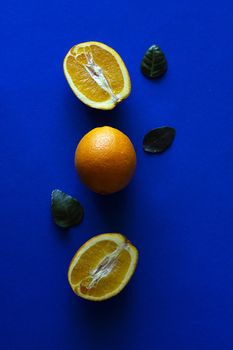 Oranges with green leaves on blue background, minimalist photography