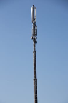 long high cell tower in front of the blue sky