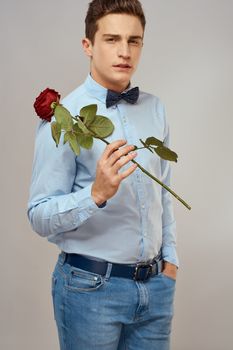 Handsome man with red rose blue shirt bow tie light background cropped view. High quality photo