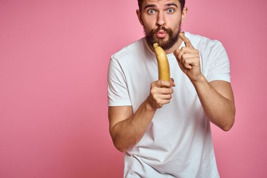 bearded man with banana in hand on pink background fun emotions model. High quality photo