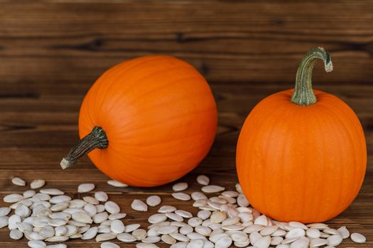 Two Pumpkins and many seeds on wooden background