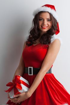 Christmas, x-mas, winter holidays concept - smiling woman in santa helper hat and dress with gift box