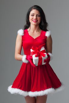 Christmas, x-mas, winter holidays concept - smiling woman in santa helper hat and dress with gift box